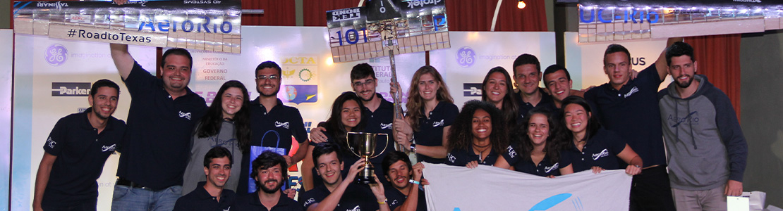 Foto da equipe segurando o avião e o troféu na cerimônia de premiação da SAE Brasil 2018.