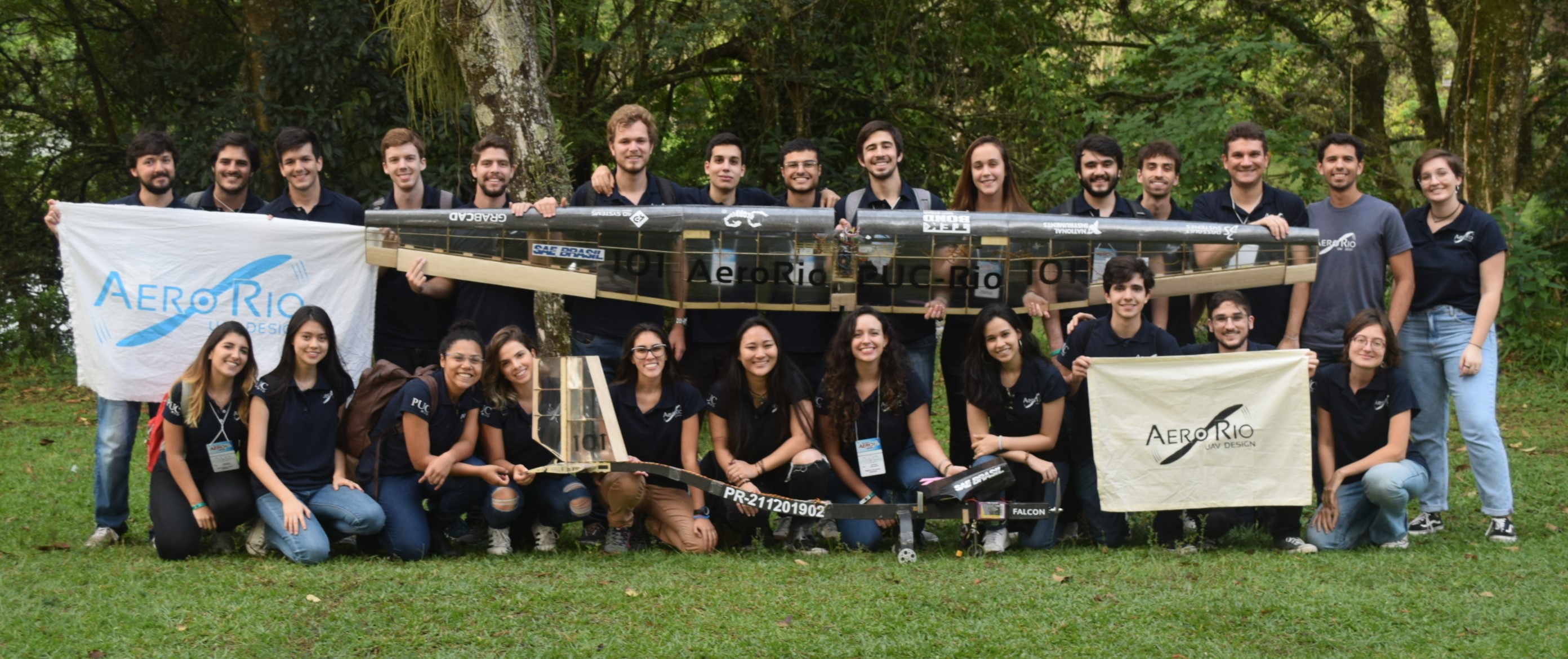 Foto da equipe segurando o avião e o troféu na cerimônia de premiação da SAE Brasil 2018.